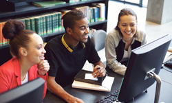 Three students work at a computer.